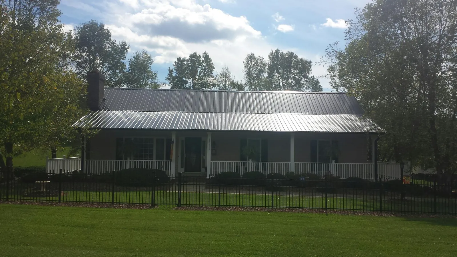Gray metal roof on a brick ranch with a full width front porch — Gutter Guard Installation work by our crew in Lee